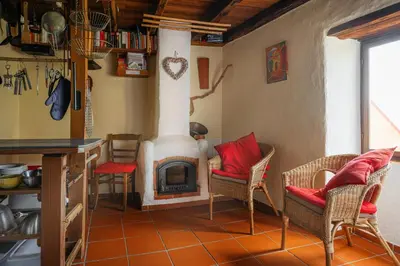 a living room with a fireplace and chairs and a table at Madeira-Meerblick-Haus in Estreito da Calheta