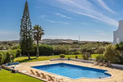 a swimming pool in a yard with chairs and a tree at Apartment Julio Pomar, swimming pool in Sagres