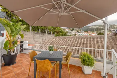 a patio with a table and chairs and an umbrella at Little Townhouse Funchal in Funchal