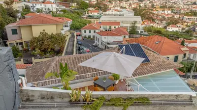 a house with a swimming pool and an umbrella at Little Townhouse Funchal in Funchal