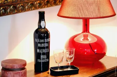a bottle of wine next to a lamp and two glasses at Apartamento Quinta do Faial in Funchal