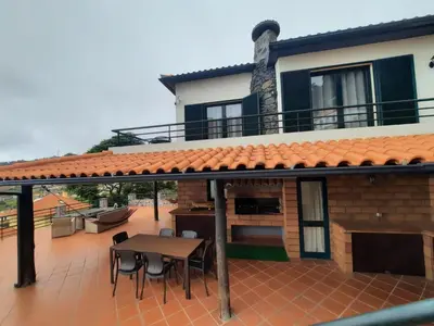 a patio with a table and a house at Casa Gama in Ribeira Brava