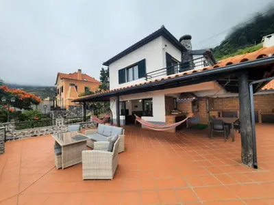 a patio with couches and hammocks on a house at Casa Gama in Ribeira Brava