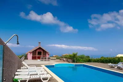 a swimming pool with lounge chairs and a house at A Casa do Lagar in São Jorge