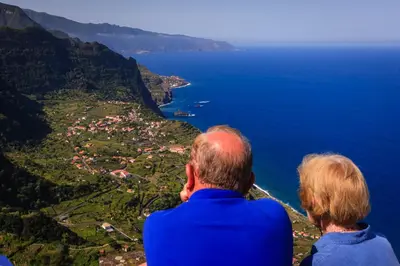 two people sitting on top of a mountain overlooking the ocean at A Casa do Lagar in São Jorge