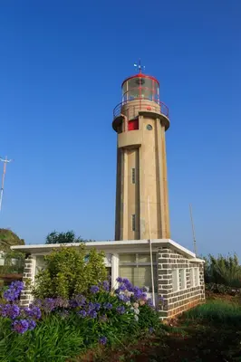 a lighthouse on top of a house with purple flowers at A Casa do Lagar in São Jorge