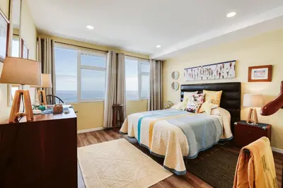 a bedroom with a bed and a desk and windows at The Waves Studios by Amazing Madeira in São Vicente