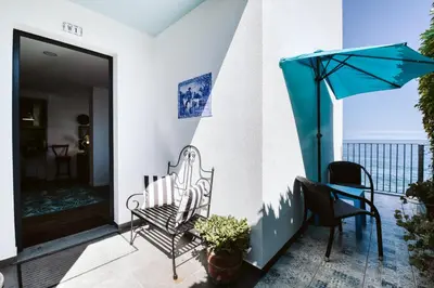 a balcony with a bench and an umbrella at The Waves Studios by Amazing Madeira in São Vicente