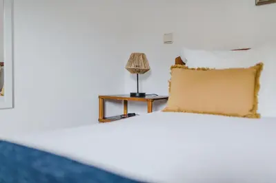a bed with a table with a lamp on it at Casinha do Paiol in Porto da Cruz
