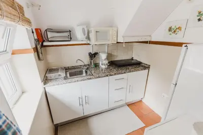 a dining room with a stove and a table at Casinha do Paiol in Porto da Cruz