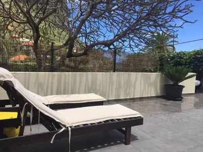 a hammock and a chair on a patio at O Clube in Porto da Cruz
