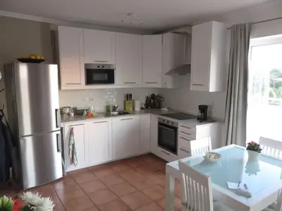 a kitchen with white cabinets and a table and a refrigerator at Sweden Apartment - Top Floor one bedroom with sea views - RS in Lagos
