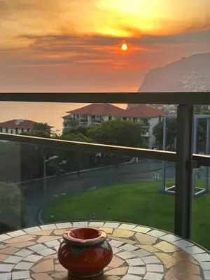 a vase sitting on a table on a balcony with a sunset at Cozy T2 with Ocean View in Funchal