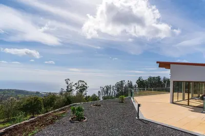 a house on top of a hill with a balcony at Rochão Village by Rent2U, Lda in Calheta