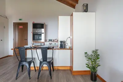 a kitchen with a table and two black chairs at Rochão Village by Rent2U, Lda in Calheta