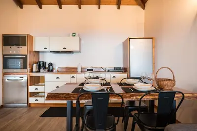 a kitchen with a table and chairs in a kitchen at Rochão Village by Rent2U, Lda in Calheta