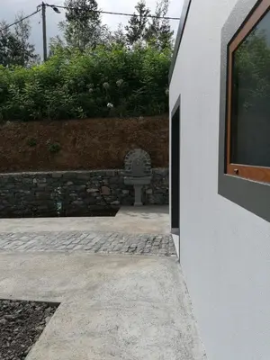 a building with a bench next to a stone wall at Rochão Village by Rent2U, Lda in Calheta