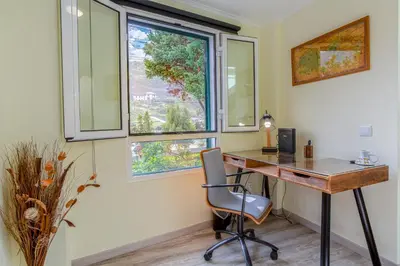 a home office with a desk and two windows at Mateus House - Porto da Cruz Center in Porto da Cruz