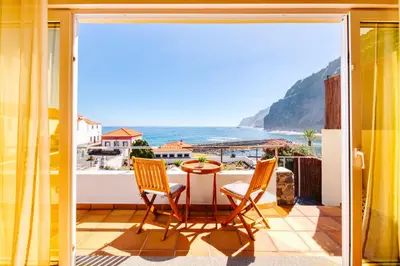 a balcony with a table and chairs and a view of the ocean at Madeira Offline by Amazing Madeira in Ponta Delgada