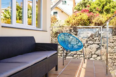 a patio with a bench and a blue chair at Madeira Offline by Amazing Madeira in Ponta Delgada