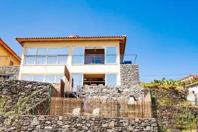 a house behind a stone wall at Madeira Offline by Amazing Madeira in Ponta Delgada