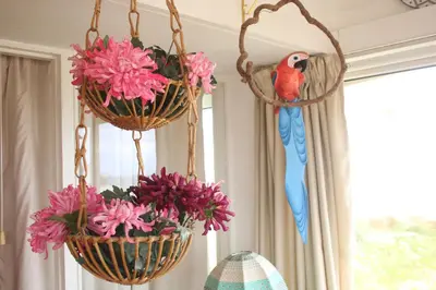 a bird is sitting on two hanging baskets with flowers at Amazing Beach House in Algarve with Sea View! in Luz