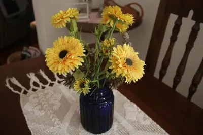 a blue vase filled with yellow flowers on a table at Amazing Beach House in Algarve with Sea View! in Luz