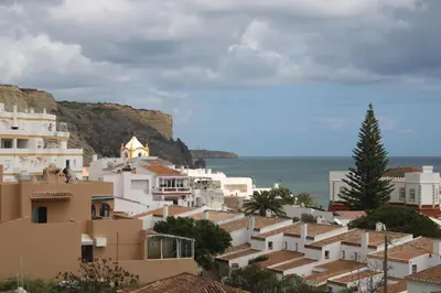 a group of buildings on a hill next to the ocean at Amazing Beach House in Algarve with Sea View! in Luz
