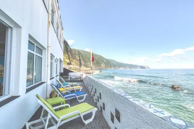 a row of chairs sitting on a wall next to the ocean at The Waves Hostel by Amazing Madeira in São Vicente