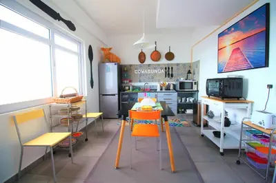 a kitchen with a table and chairs and a refrigerator at The Waves Hostel by Amazing Madeira in São Vicente