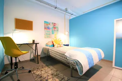 a bedroom with a bed and a desk and a chair at The Waves Hostel by Amazing Madeira in São Vicente