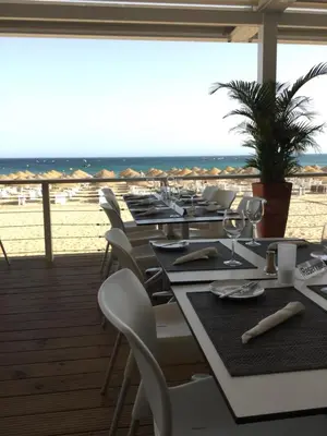 a row of tables and chairs with the beach in the background at OCEAN VIEW VILLA BELAMAR in Luz