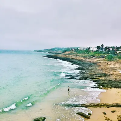 a person standing on a beach next to the ocean at OCEAN VIEW VILLA BELAMAR in Luz