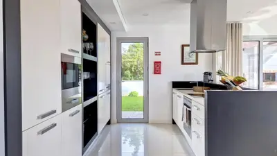 a kitchen with white cabinets and a door leading to a yard at Villa Madeira by LovelyStay in Caniço