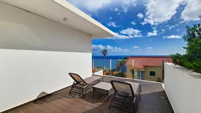a balcony with chairs and a table and the ocean at Villa Madeira by LovelyStay in Caniço