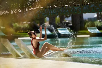 a woman in a bathing suit sitting on a water fountain at Savoy Palace - The Leading Hotels of the World - Savoy Signature in Funchal