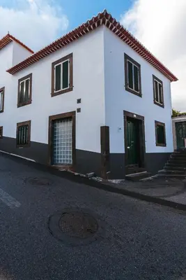 a white house with green doors on a street at Fortaleza do Pico Apartment in Funchal
