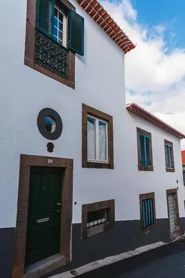 a white building with a green door and windows at Fortaleza do Pico Apartment in Funchal