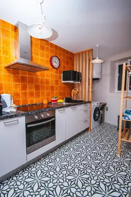 a kitchen with orange tiled walls and white cabinets at Fortaleza do Pico Apartment in Funchal
