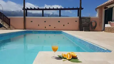 a glass of orange juice next to a swimming pool at Quintinha do Álvaro - Holiday house in Santana