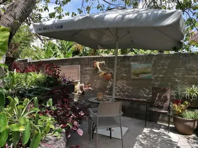 a patio with an umbrella and a chair and some plants at Casa do pescador in Machico