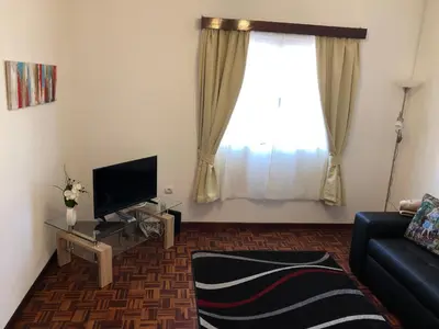 a living room with a couch and a tv and a window at City View Gardens II in Funchal