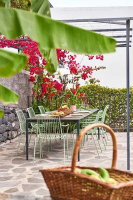 a table and chairs with red flowers on a patio at Bordal Houses in Funchal