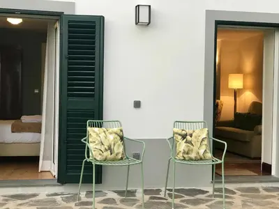 two chairs sitting next to a room with a bed at Bordal Houses in Funchal