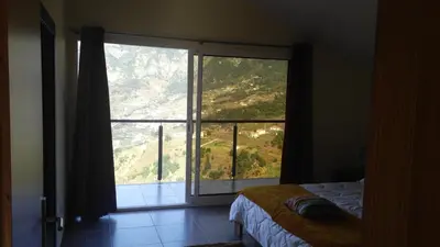a bedroom with a large window with a mountain view at Matilde House in São Vicente