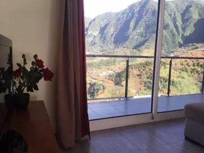 a room with a large window with a view of a mountain at Matilde House in São Vicente