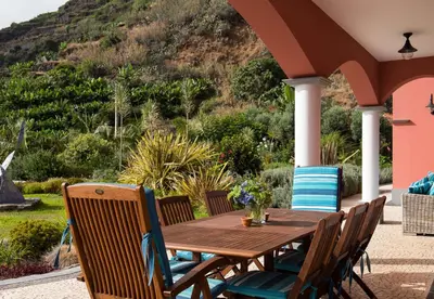 a wooden table and chairs on a patio at Luxury Ocean Front Villla in Calheta