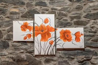 three paintings of orange flowers hanging on a stone wall at King's House - Centennial House in Arco da Calheta