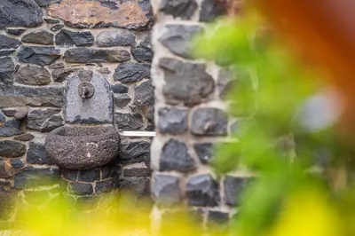 an old bell on the side of a stone wall at King's House - Centennial House in Arco da Calheta