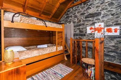 a bedroom with two bunk beds and a table and a chair at King's House - Centennial House in Arco da Calheta